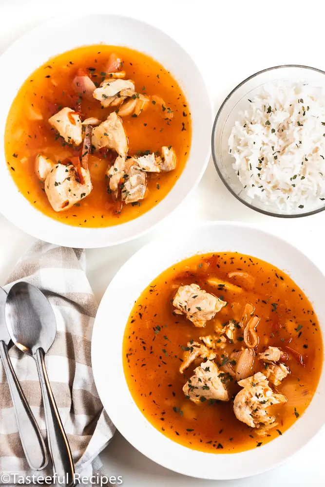 Overhead shot of tomato fish stew with a bowl of rice