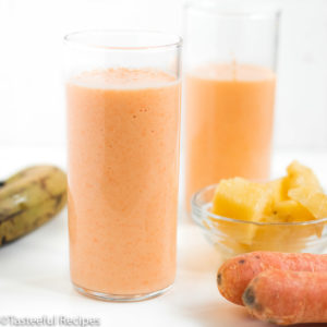 Straight on shot of two glasses of tropical carrot smoothie