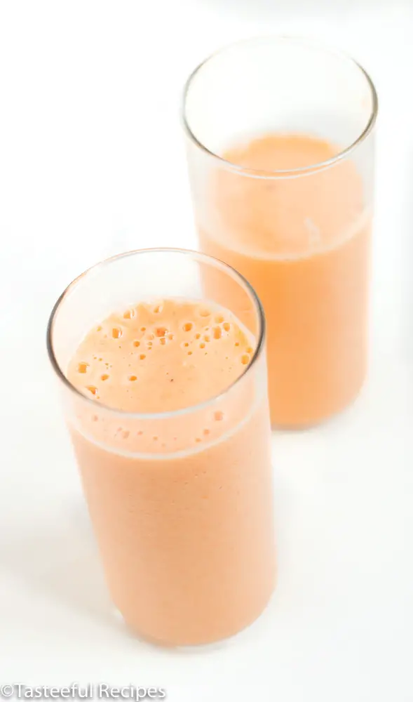 Angled shot of two glasses of tropical carrot smoothie
