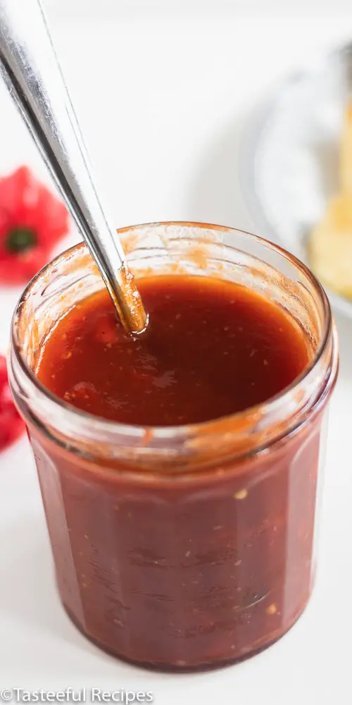 Angled shot of a spicy pineapple bbq sauce in a jar with a spoon