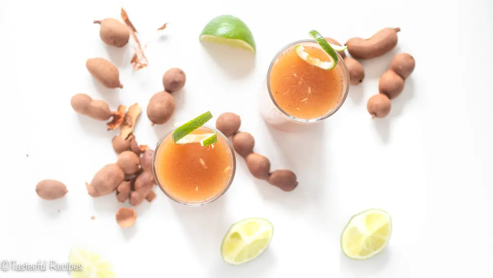 Overhead shot of glass filled with homemade tamarind juice garnished with lime swirls