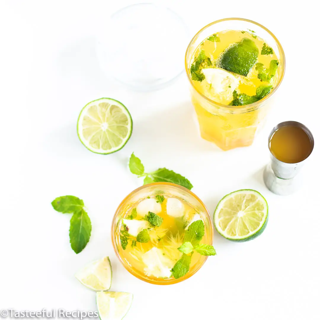 Overhead shot of two virgin passion fruit mojitos in glasses garnished with mint leaves and lime wedges