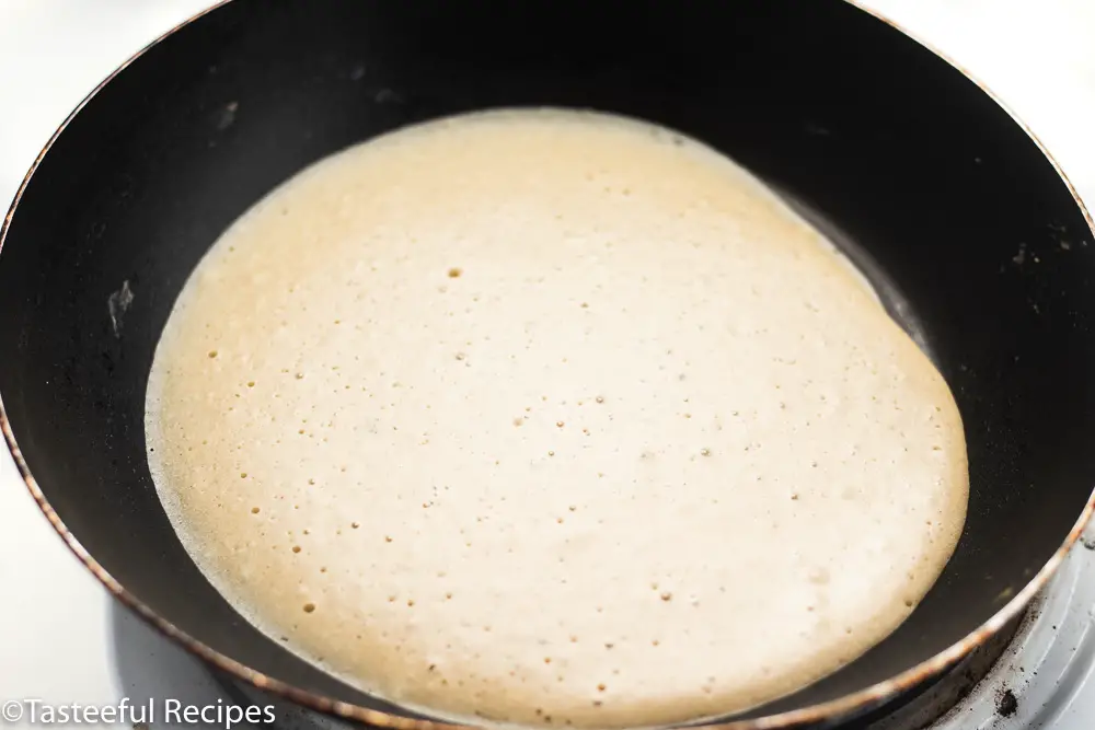 Angled shot of crepes being cooked in a pan 