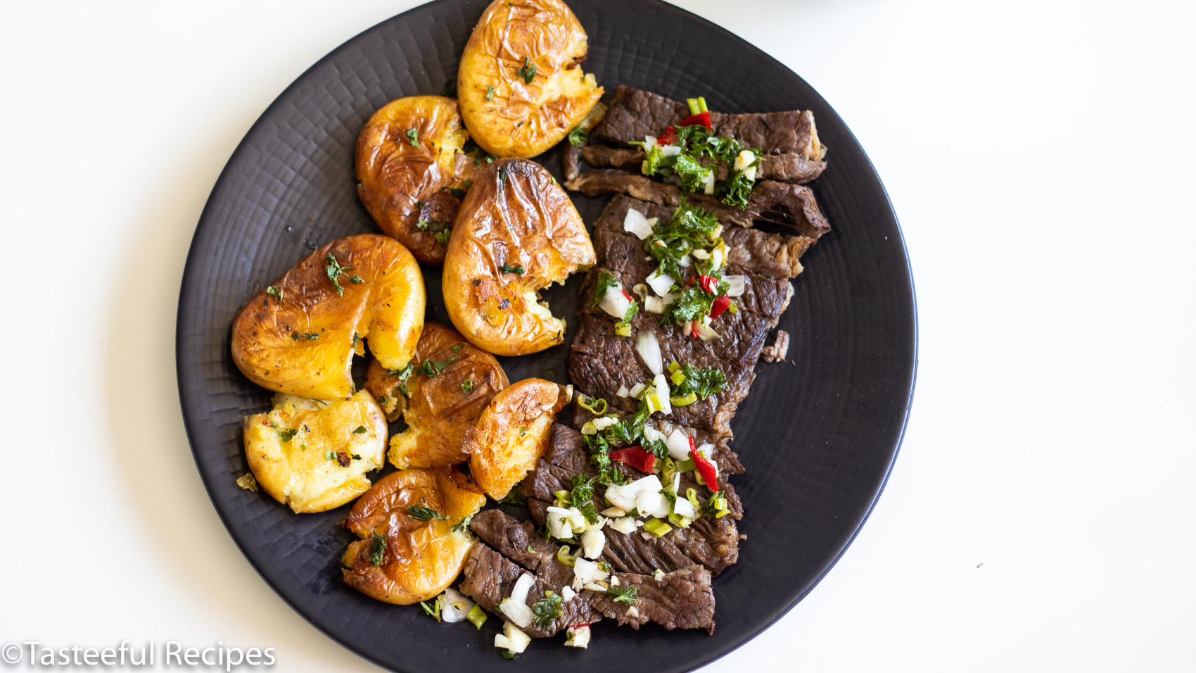 Overhead shot of steak and potatoes with a bowl of sauce chien