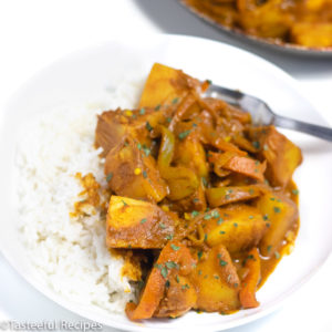 Angled shot of a plate of curry breadfruit served with white rice