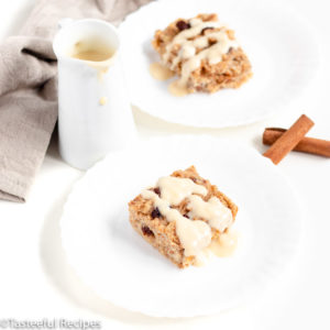 Angled shot of two plates of caribbean-style bread pudding topped with a rum sauce