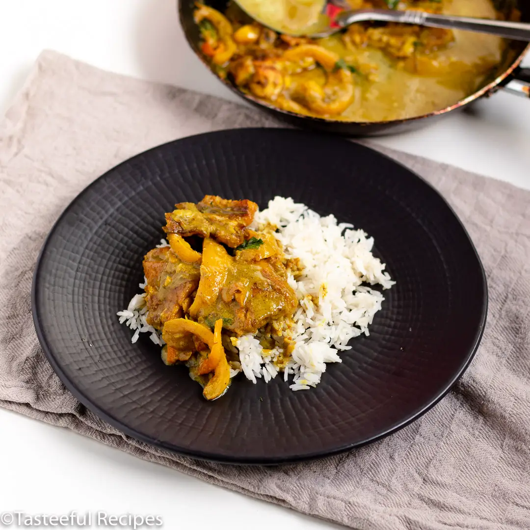 Angled shot of a plate of coconut curry fish served with white rice