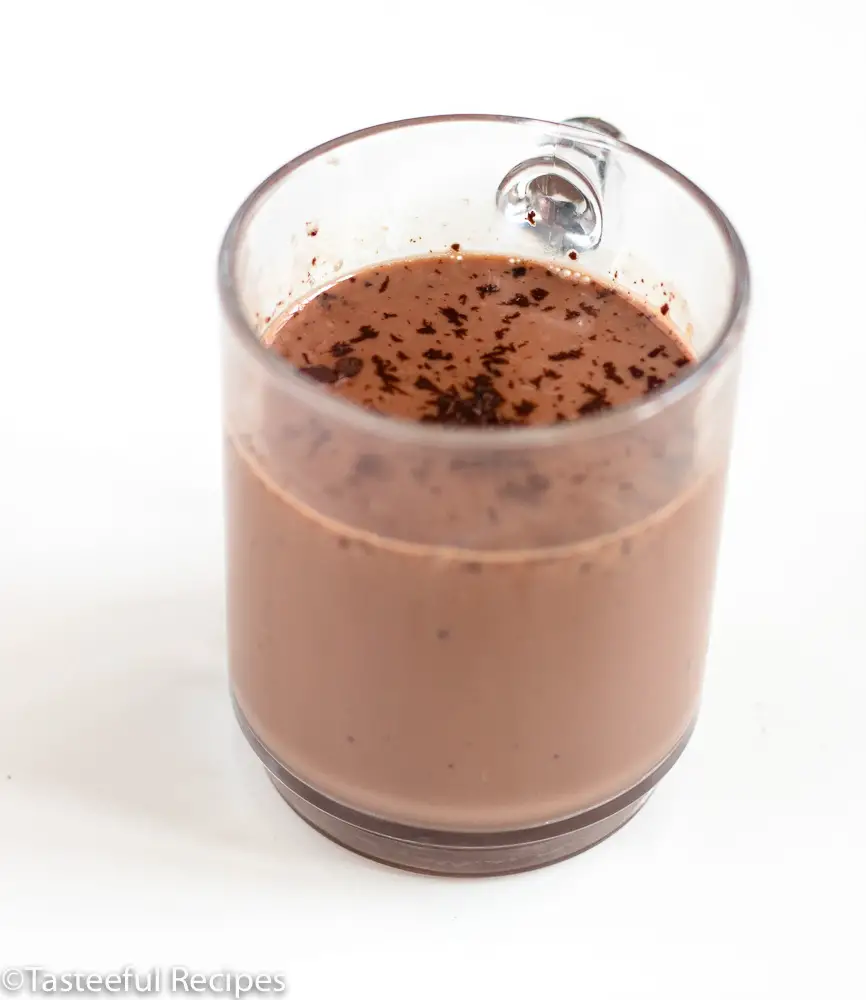 Angled shot of a glass mug filled with creamy creole hot chocolate