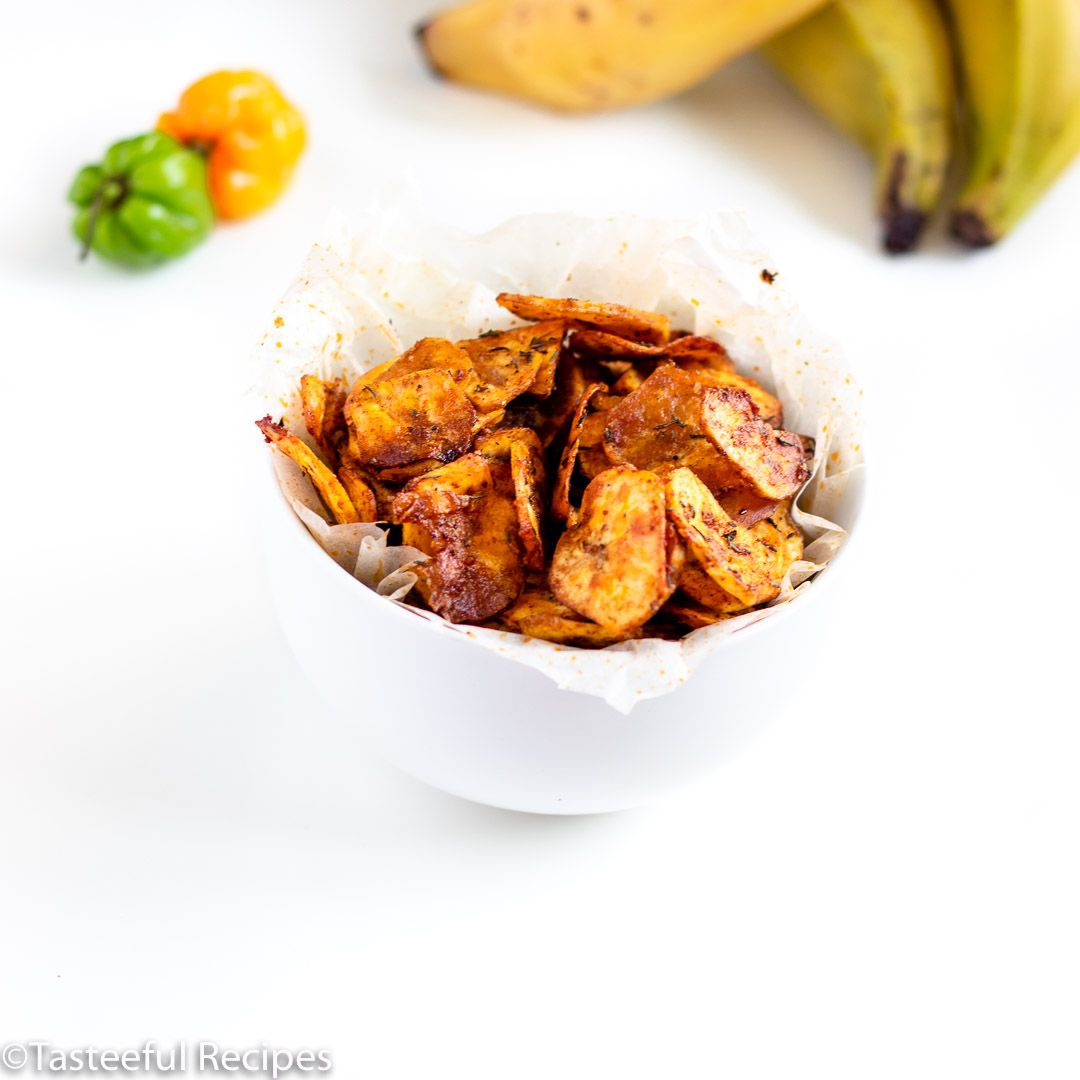 Angled shot of a bowl of baked jerk plantain chips