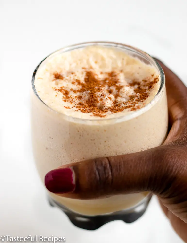 Straight on shot of a glass of eggnog being held