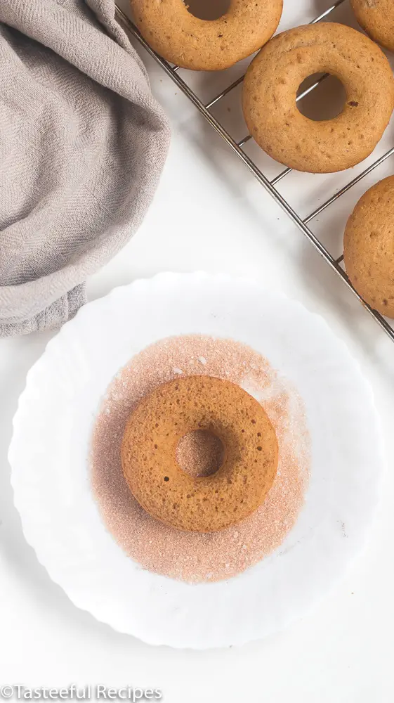 Overhead shot of donut being coated in cinnamon sugar