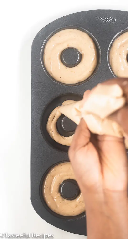 Overhead shot of donuts being poured into baking pan