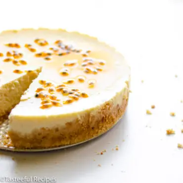 Straight on shot of a whole passion fruit cheesecake topped with passion fruit seeds