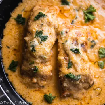 Close up shot of salmon in a frying pan covered in a coconut mango sauce