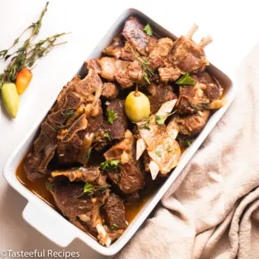 Overhead shot of stewed Caribbean goat meat in a baking pan