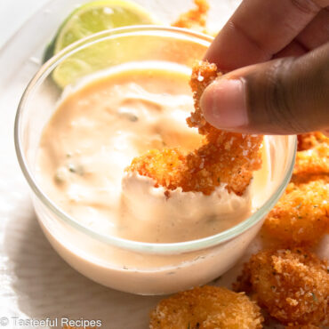 Angled shot of a shrimp being dipped in a Caribbean style shrimp cocktail sauce