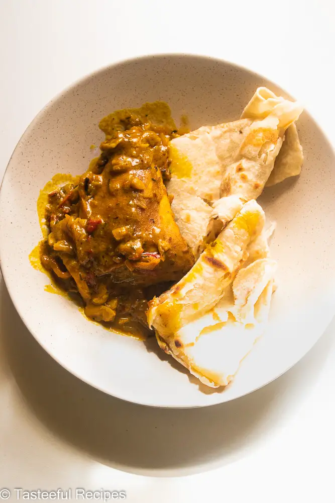 Overhead shot of a plate of curry chicken and guyanese style roti